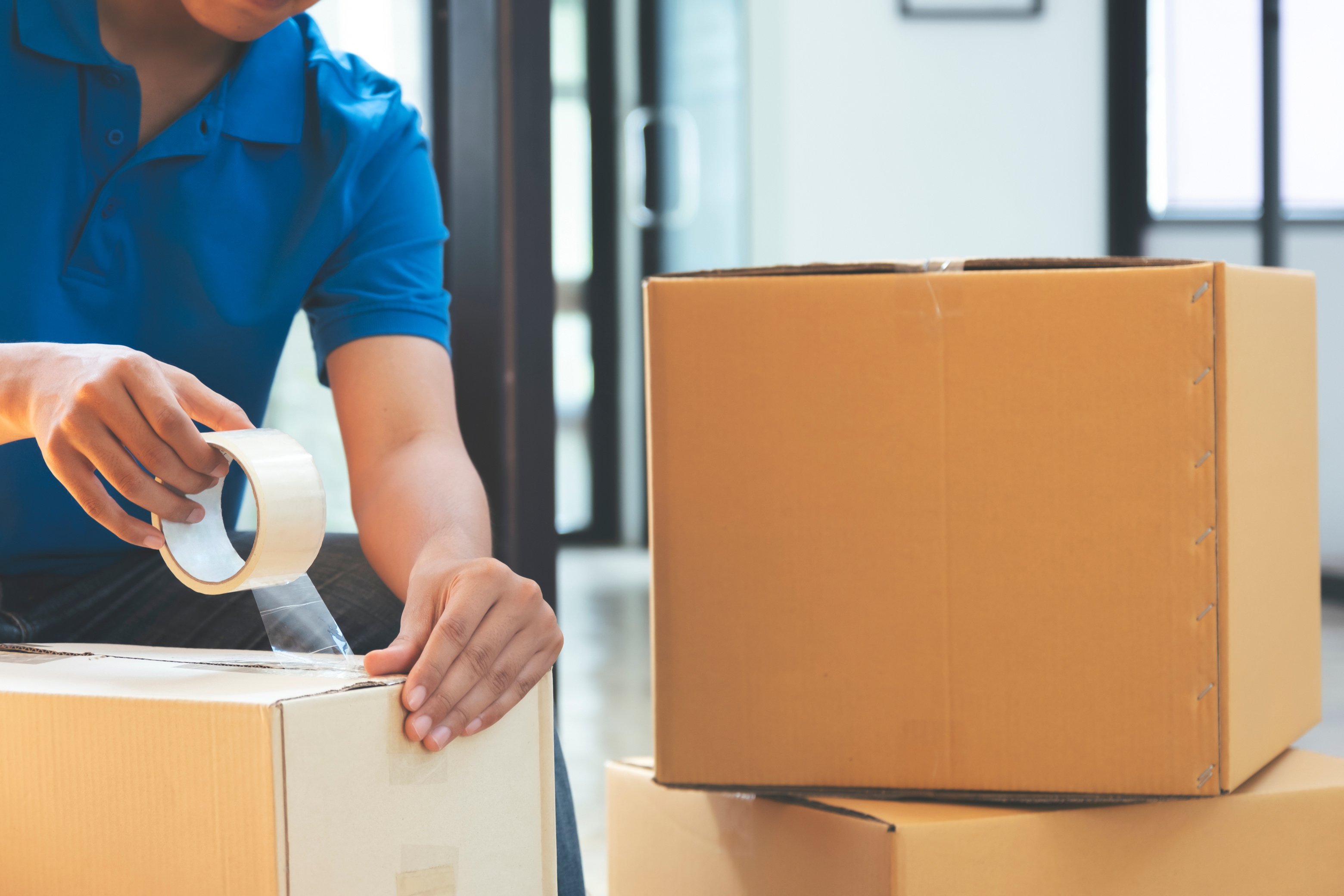 Man Placing Packaging Tape on a Carton Box